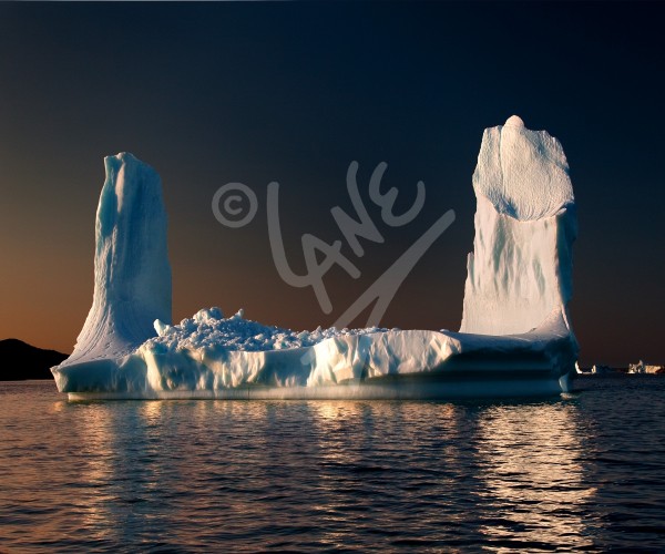 Iceberg with twin towers at sunset